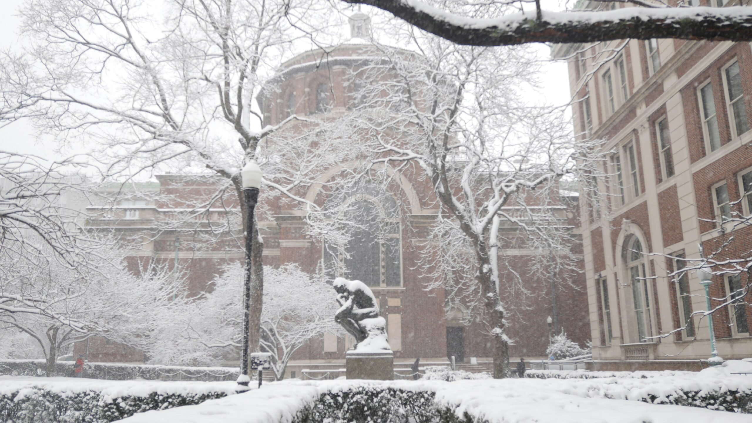 a snow covered campus with a statue in the foreground