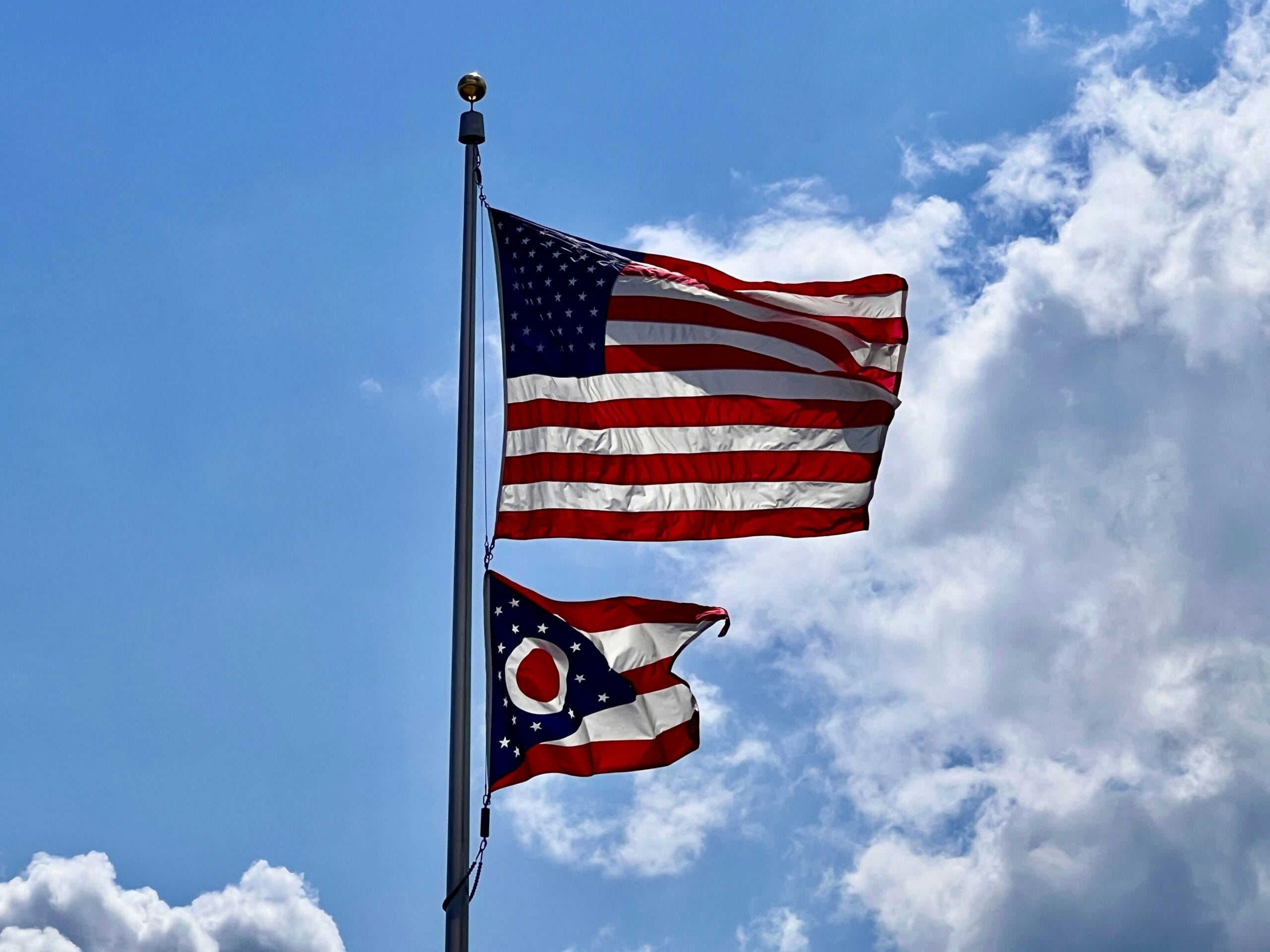 Two flags flying in the wind on a cloudy day