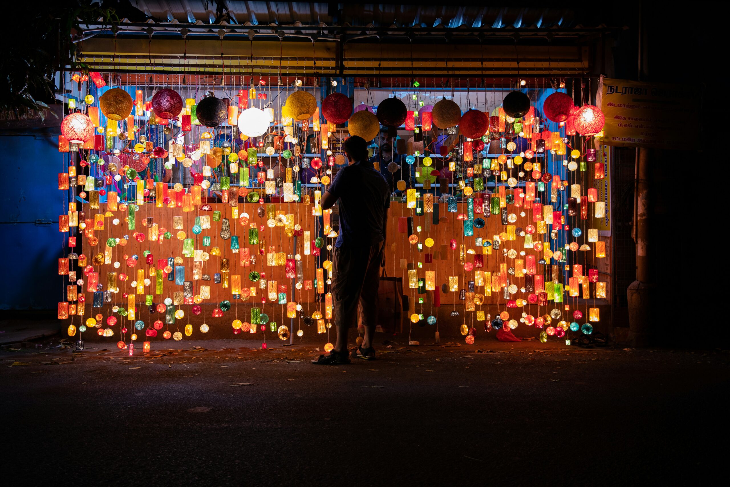 man in black jacket standing in front of red and yellow heart shaped wall decor