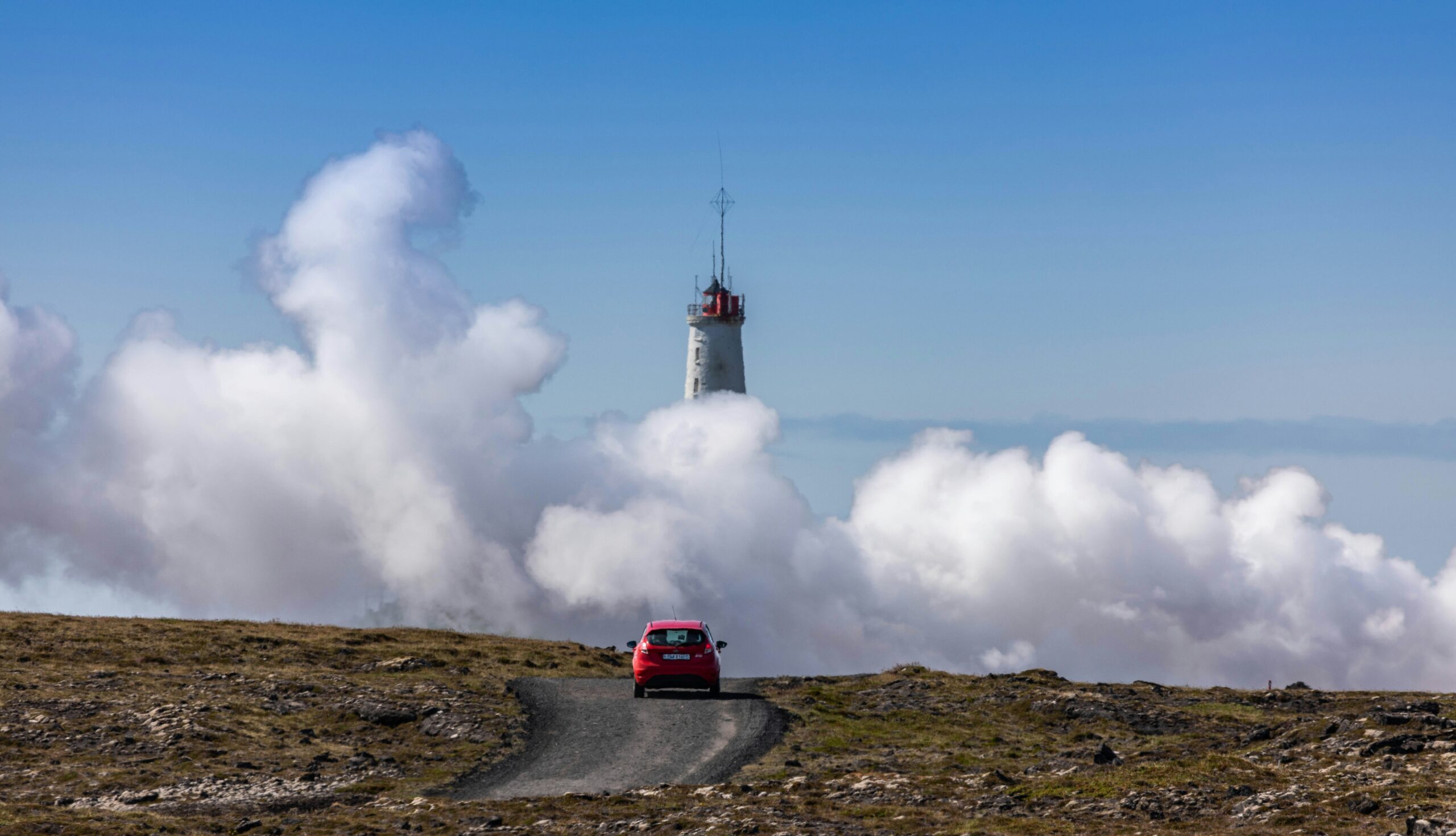 red vehicle on road near large smoke during daytime