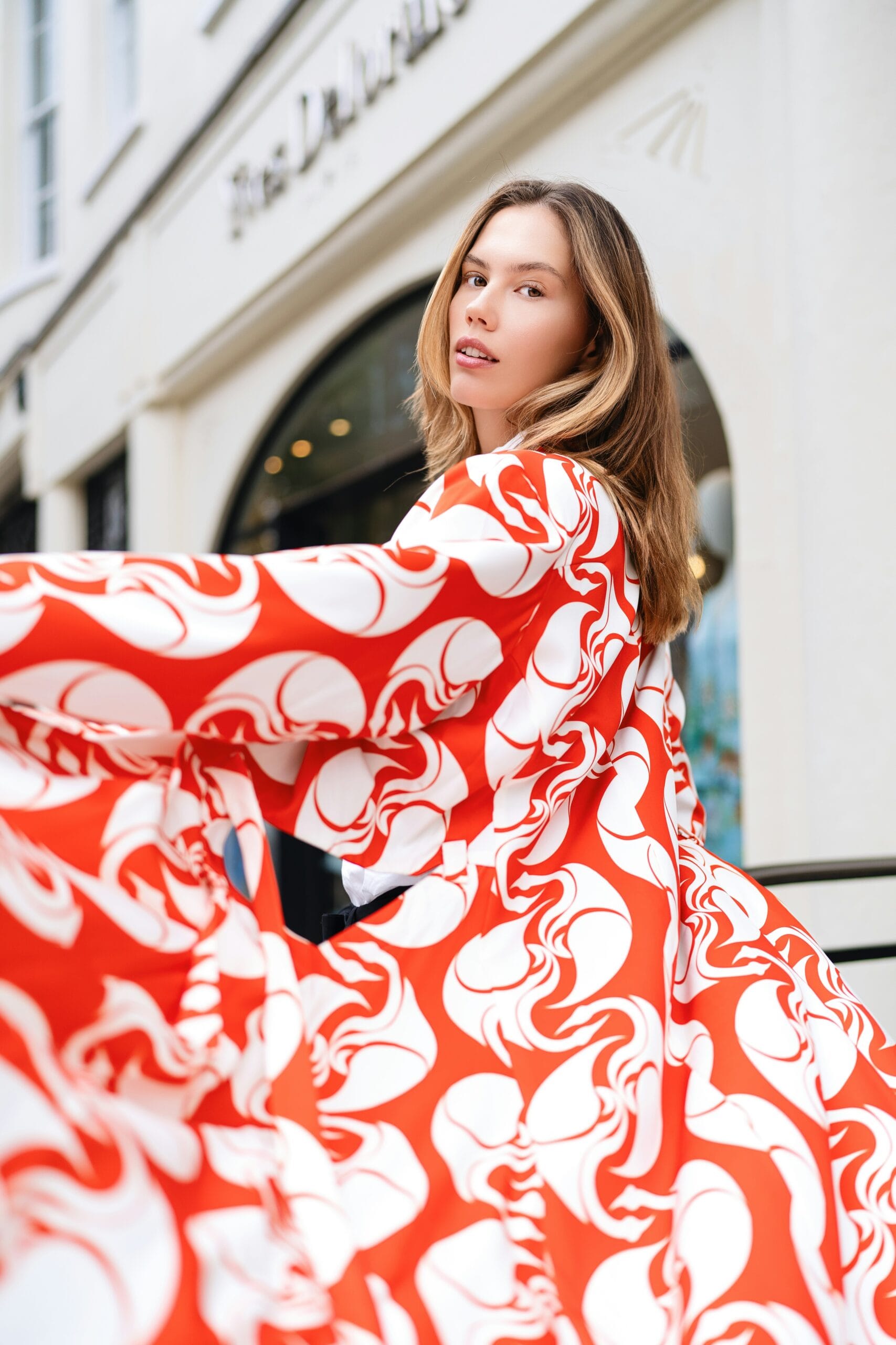 A woman in a red and white dress is standing outside