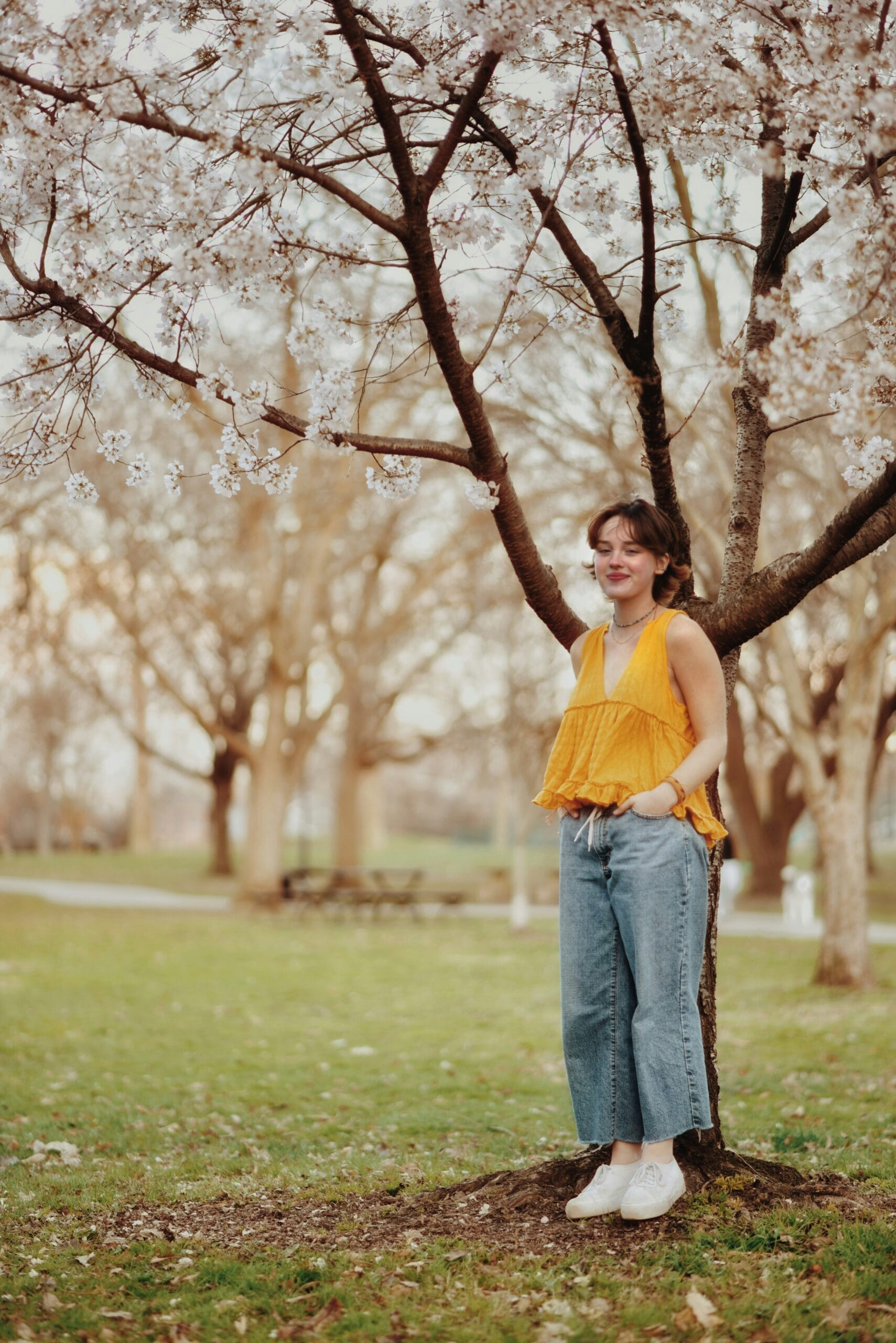 a woman standing next to a tree in a park